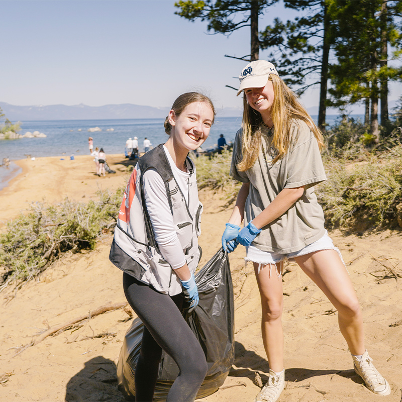 Volunteers haul a bag of litter off the beach.